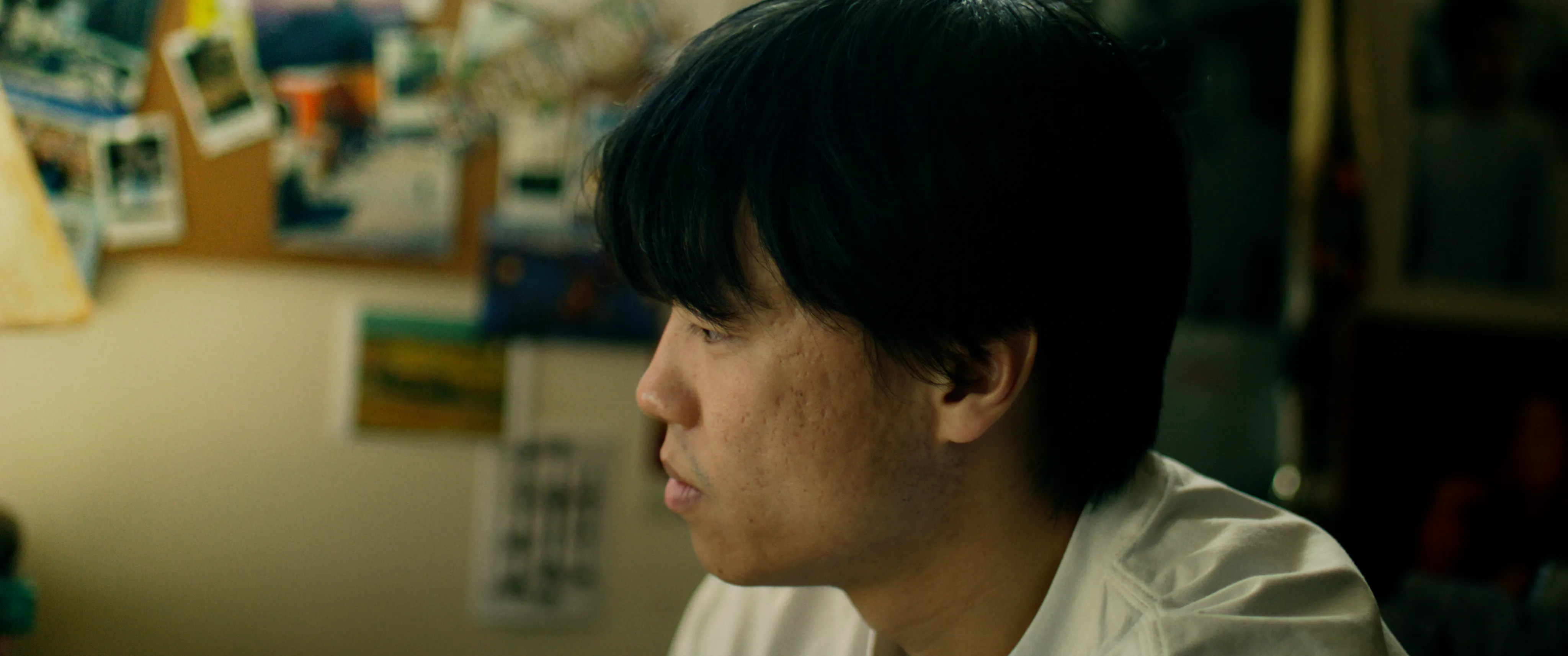 A man in profile in a softly lit room.