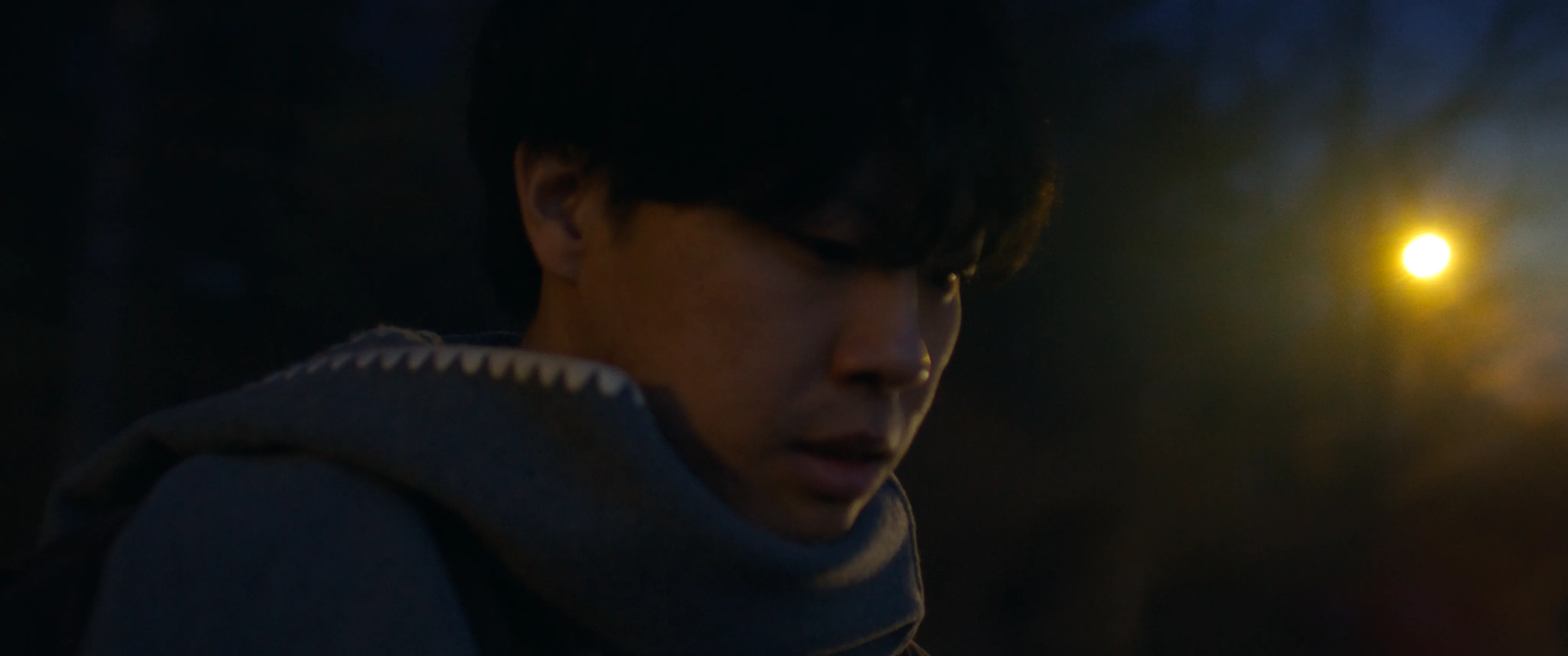 A man wearing a scarf at night.