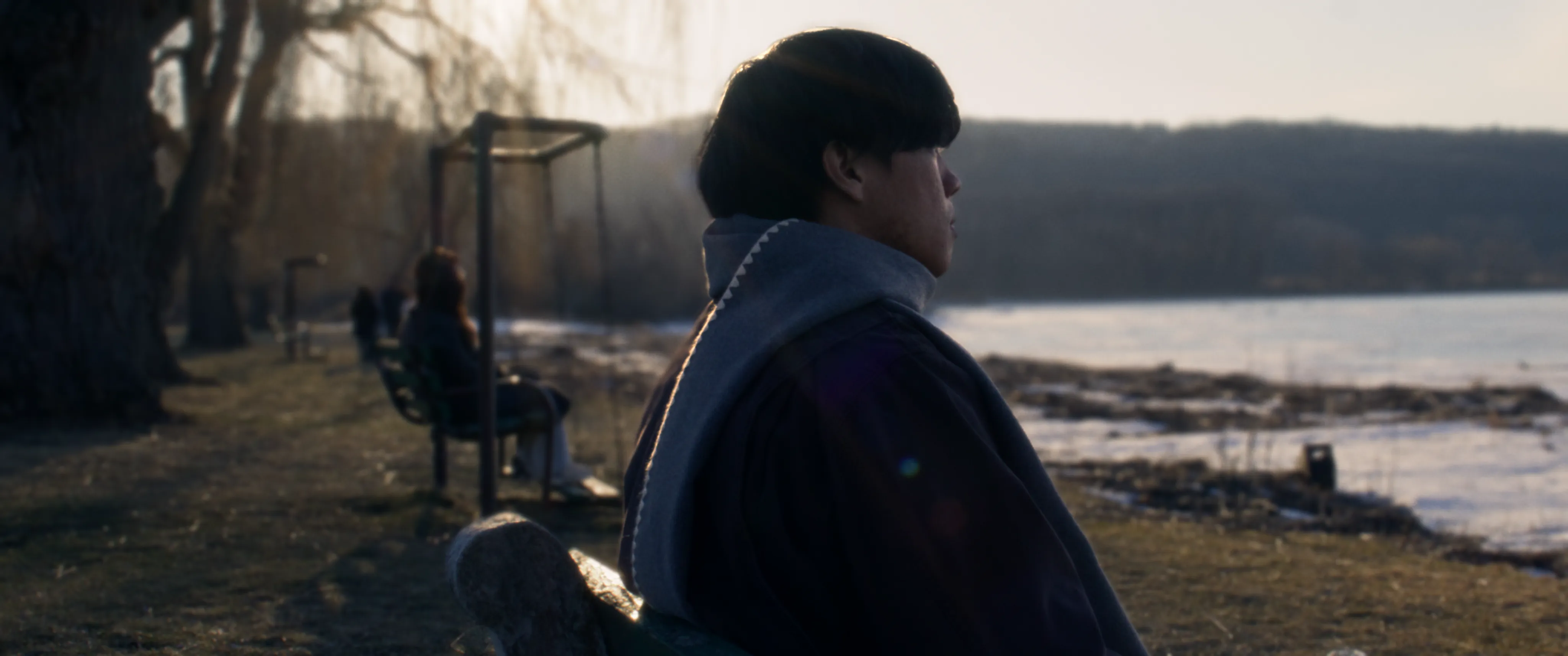 A man beside a lake in winter sunlight.