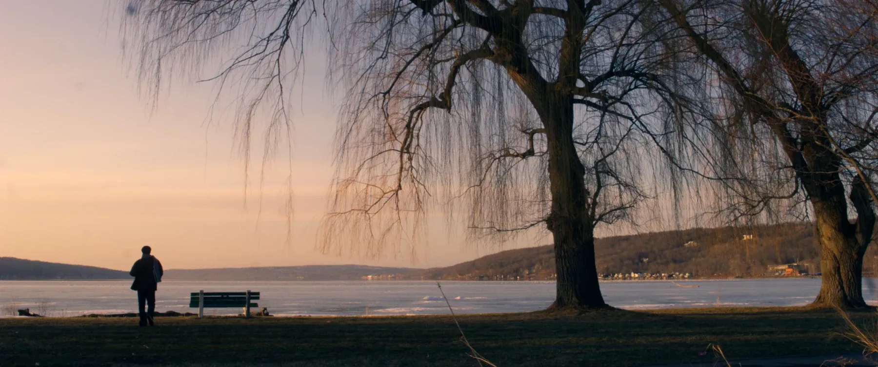 A figure beside the lake at sunset.